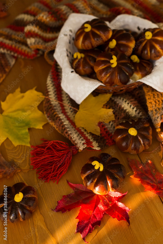 Naklejka premium Homemade apple cakes in the shape of pumpkins, cosy colorful shawl or scarf and autumn leaves