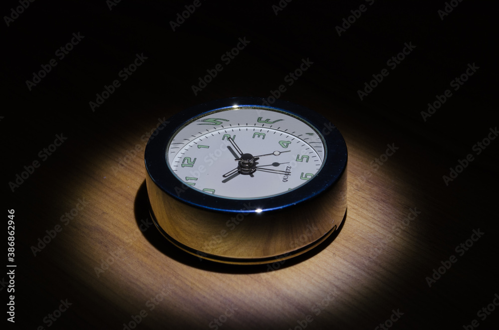 spotlght on the face of an analogue chrome travel clock spotlght on the face of an analogue chrome travel clock