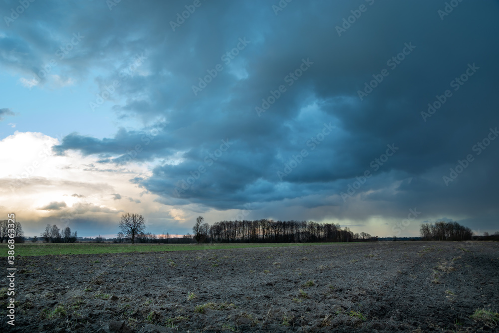 Dark rain cloud over a plowed field