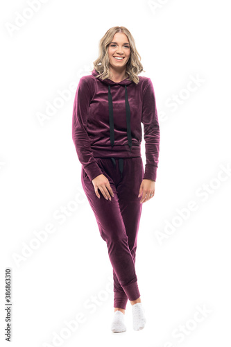 Candid spontaneous laughing young woman in comfy home clothes wearing tracksuit and socks. Full body isolated on white background.