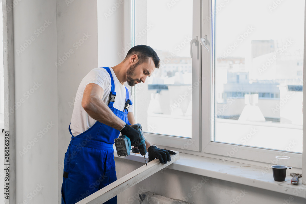A man in blue work clothes stands against the wall and showing thumb A man in blue work clothes stands against the wall and showing thumb