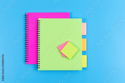 Two notebooks with colourful stickers on blue horizontal background. Copy space