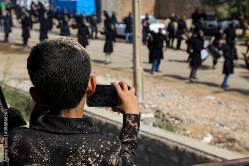 Fotomurale a child filming the ritual of Ashura