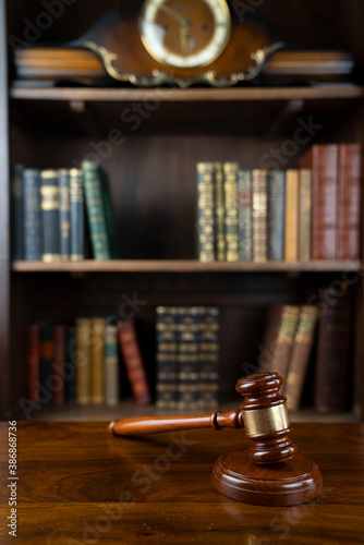 Law theme. Judge chamber. Gavel on brown desk. Collection of legal books in the bookshelf.