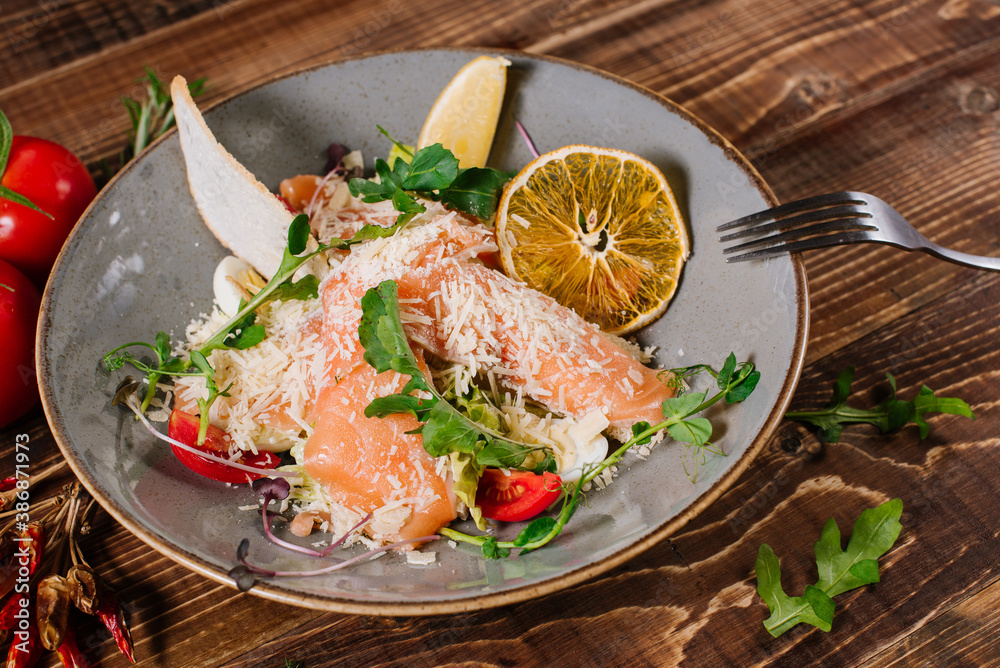 A dish with salmon, vegetables and herbs on wooden background A dish with salmon, vegetables and herbs on wooden background