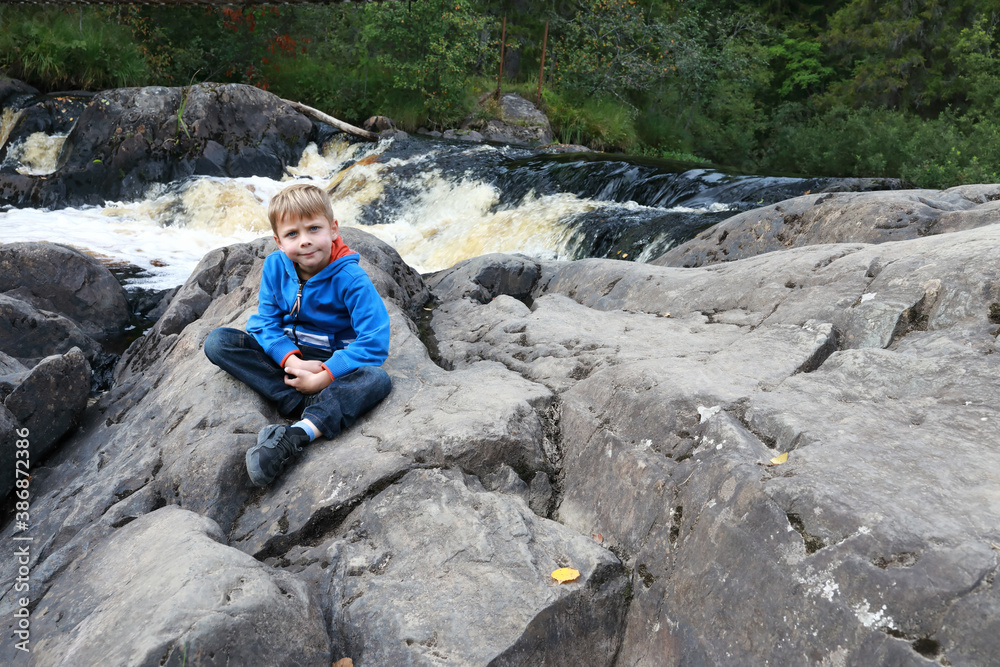 Child on background of Ruskeala waterfall
