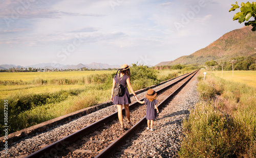 Tableau sur toile Mother with the daughter go on rails, back to a camera, on nature, in the summer