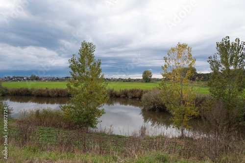 Landscape photo with water trees and an ominous cloudy sky