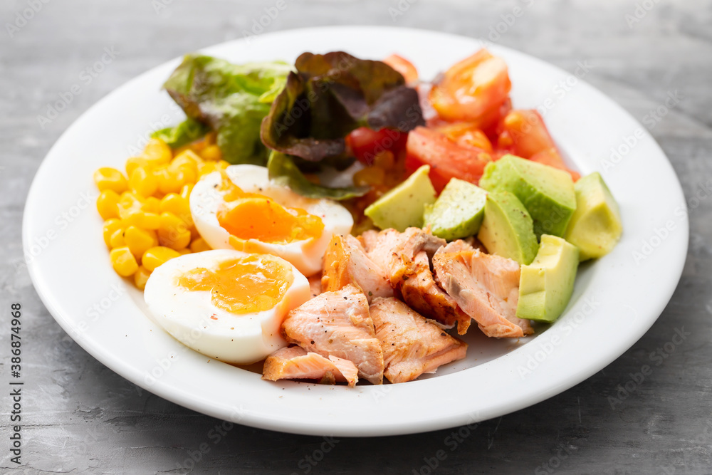 salad salmon with vegetables and boiled egg on white plate on ceramic background salad salmon with vegetables and boiled egg on white plate on ceramic background