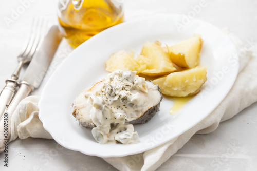 boiled fish with sauce tartar and boiled potato on white dish