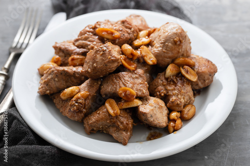 meat with nuts on white plate on ceramic background