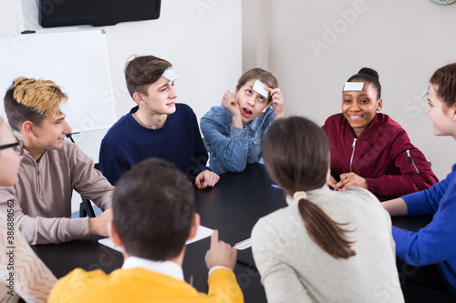 happy classmates having round of guess-who game during class