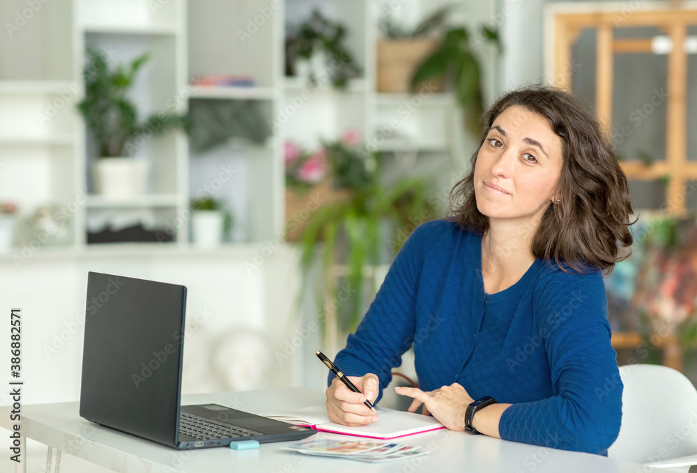 A young brunette woman uses a laptop in her office or at home. A young brunette woman uses a laptop in her office or at home.