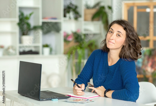 A young brunette woman uses a laptop in her office or at home.