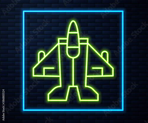 Glowing neon line Jet fighter icon isolated on brick wall background. Military aircraft. Vector.