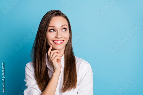 Photo of pretty lady good mood finger on cheek look up empty space think wear white shirt isolated blue color background