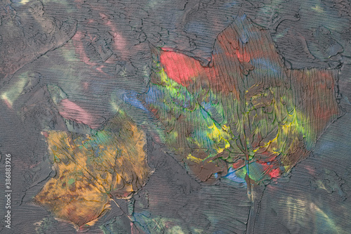 Odbite liście klonu w farbie w namalowanym wielokolorowym abstrakcyjnym tle faktury
