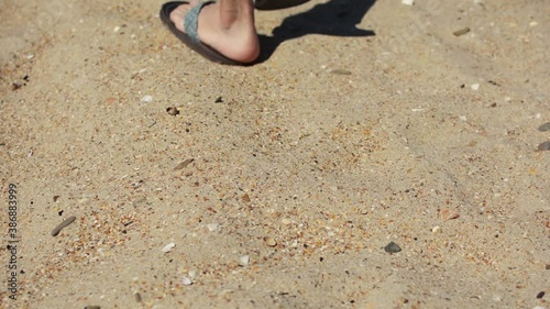 Beach travel concept – man walking away on beach sand coastline and camera follows footprints. Footsteps on sand during summer vacation. Video of Bugaz Spit, Anapa – Russia seascape.  photo