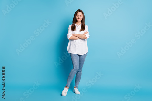 Full body photo of charming lady arms crossed friendly wear white shirt jeans shoes isolated blue color background