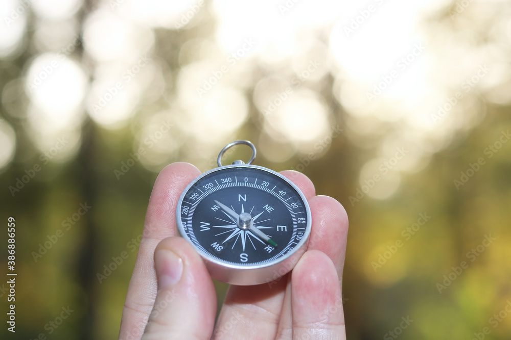 Old classic navigation compass in hand on natural background with bokeh as symbol of tourism with compass, travel with compass and outdoor activities with compass Old classic navigation compass in hand on natural background with bokeh as symbol of tourism with compass, travel with compass and outdoor activities with compass