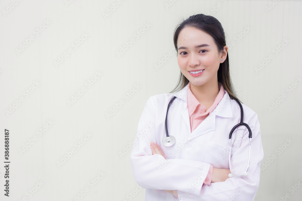 Young beautiful Asian woman doctor Standing with arms crossed happy and smile in hospital. Wearing a white robe and stethoscope Young beautiful Asian woman doctor Standing with arms crossed happy and smile in hospital. Wearing a white robe and stethoscope