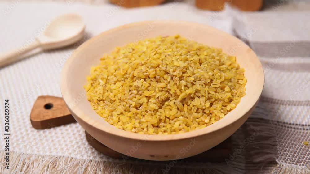 bulgur in a wooden bowl on wooden table, rustic style. Bulgur wheat grains bulgur in a wooden bowl on wooden table, rustic style. Bulgur wheat grains