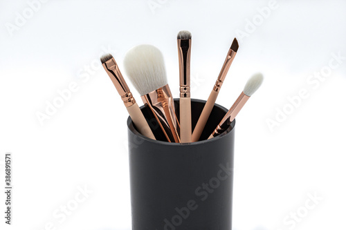 makeup brushes in a black glass. White background.