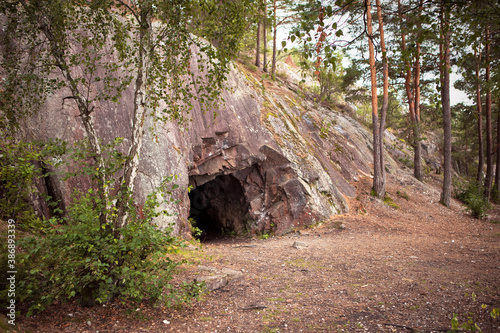 Obraz na płótnie Landscape with cave and forest. Scenic entrance to cave. Rock wall with a dark hole. Spro, Mineral historic mine. Nesodden Norway. Nesoddtangen peninsula. w salonie