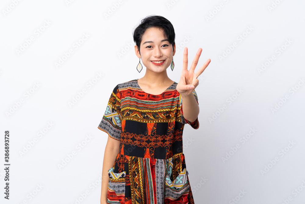 Young Asian girl with a colorful dress over isolated white background happy and counting three with fingers Young Asian girl with a colorful dress over isolated white background happy and counting three with fingers