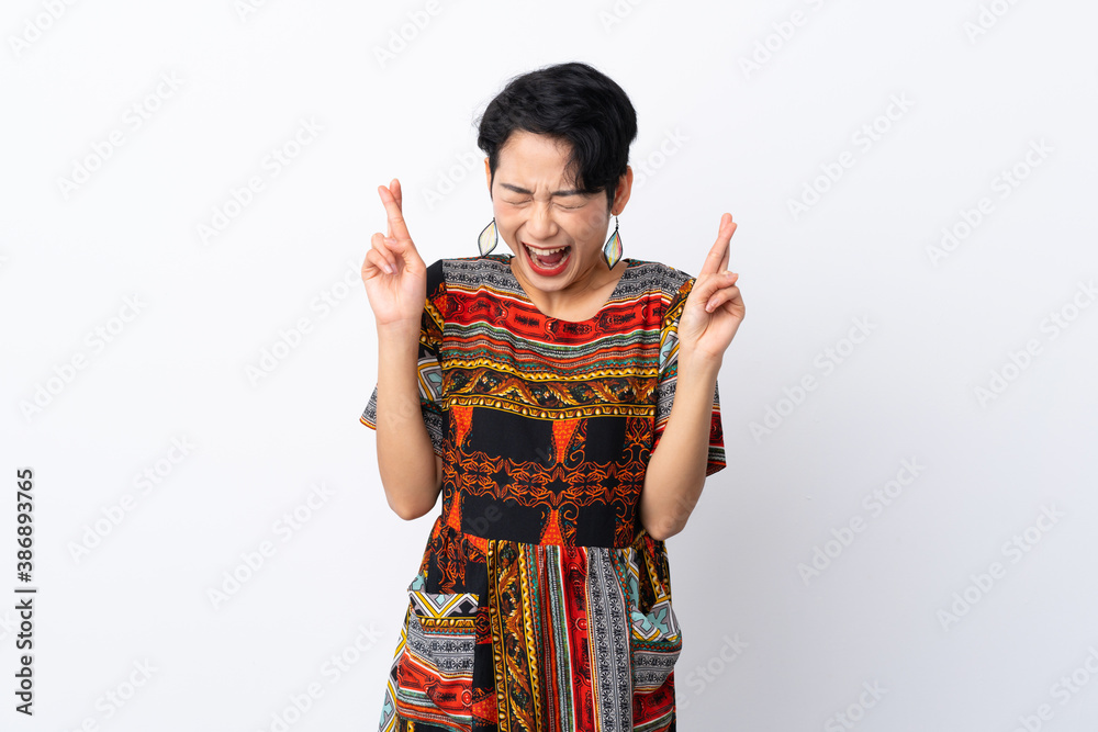 Young Asian girl with a colorful dress over isolated white background with fingers crossing Young Asian girl with a colorful dress over isolated white background with fingers crossing
