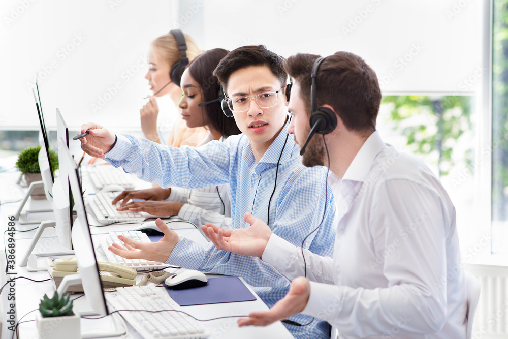 User support service concept. Hotline operator helping his coworker at call centre User support service concept. Hotline operator helping his coworker at call centre