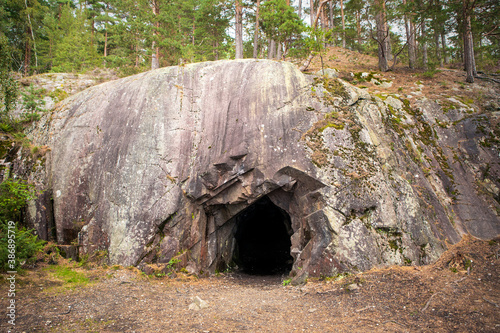 Landscape with cave and forest. Scenic entrance to cave. Rock wall with a dark hole. Spro, Mineral historic mine. Nesodden Norway. Nesoddtangen peninsula.