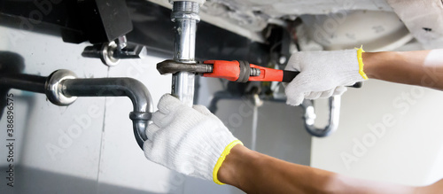 Schilderij op canvas Plumber fixing white sink pipe with adjustable wrench.