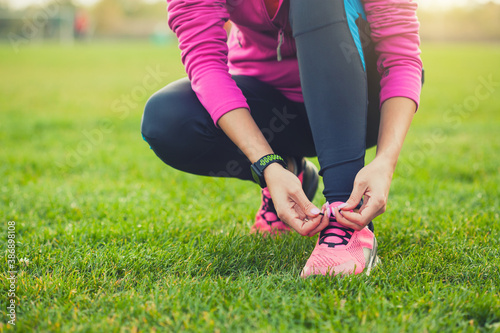 woman athlete tying shoelaces on sneakers on the green meadow