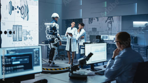 Wallpaper Mural In Robotics Development Laboratory: Engineers and Scientists Work on a Bionics Exoskeleton Prototype with Person Testing it. Designing Wearable Exosuit to Help Disabled People, Warehouse Workers Torontodigital.ca