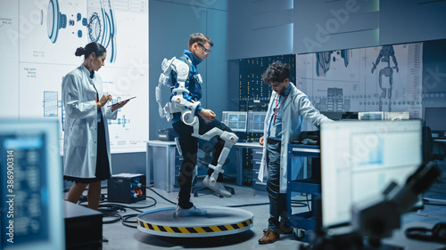 In Robotics Development Laboratory: Engineers and Scientists Work on a Bionics Exoskeleton Prototype with Person Testing it. Designing Wearable Exosuit to Help Disabled People, Warehouse Workers photo