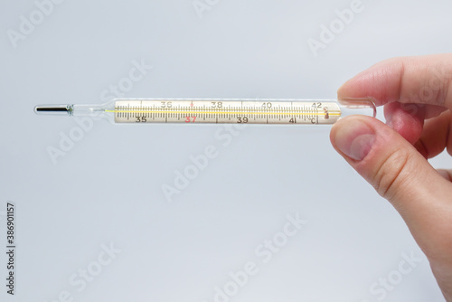 mercury thermometer in the hand of a man isolated on a blue background. Temperature measurement using a thermometer. High fever and illness. Close up