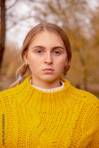 Facial portrait of a blonde girl on a blurry background of nature.
