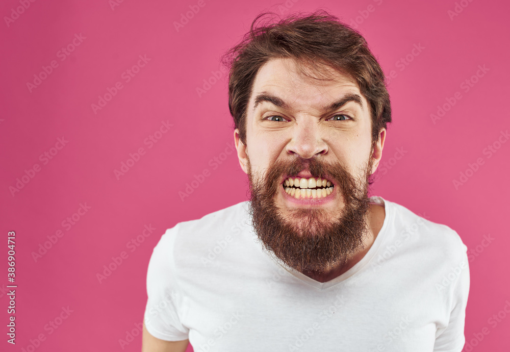An angry man with a bushy beard bared his teeth against a pink background An angry man with a bushy beard bared his teeth against a pink background