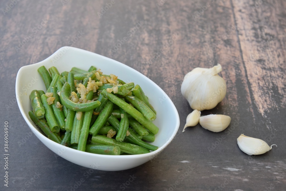 Sautéed green beans with garlic in a bowl on wooden background Sautéed green beans with garlic in a bowl on wooden background