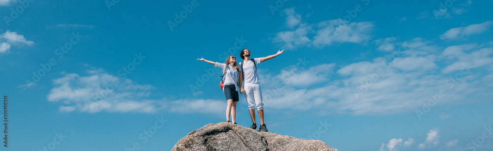 A couple stand on a rock at a viewpoint with an epic view of the ocean