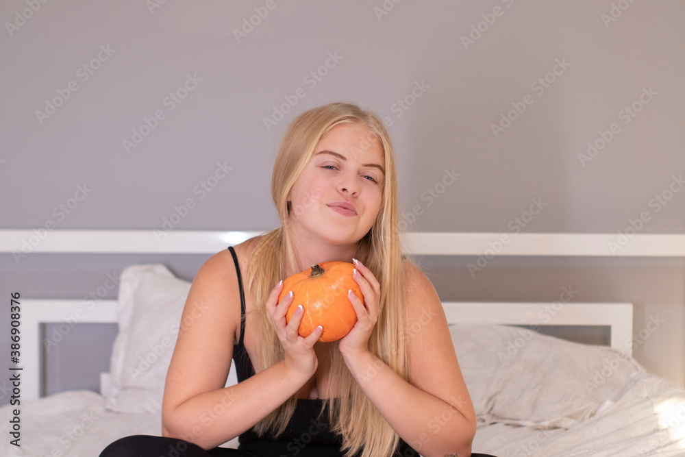 beautiful blonde with pumpkin in white bedroom. halloween concept. beautiful blonde with pumpkin in white bedroom. halloween concept.