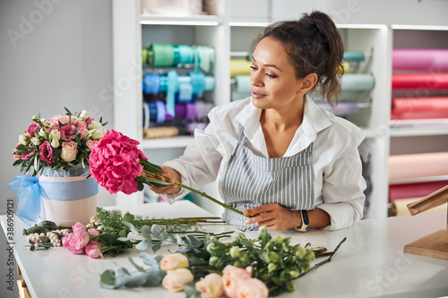Enthusiastic female florist making a bouquet of pretty flowers photo