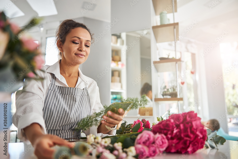Concentrated female florist choosing flowers for floral creations
