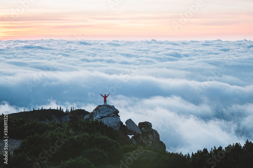 Young woman hiker enjoy the view on mountain peak. Happy traveler hipster standing on top of sunny mountains. Atmospheric moment. Travel, freedom and happiness