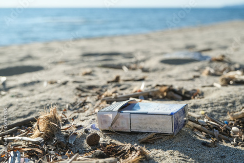 Dirty cigarette pack trash discarded on sea coast ecosystem,environmental pollution issues