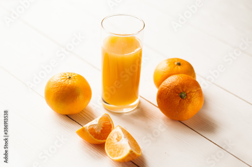 Glass of fresh tangerine juice and fruits on marble table. Glass of orange juice with some tangerines.