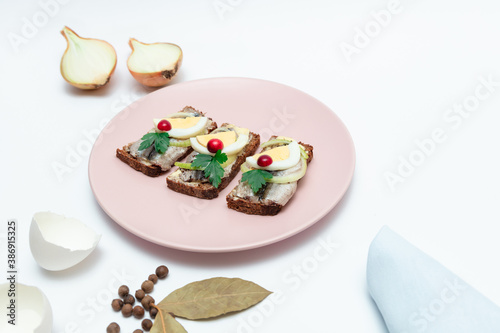 Spice Baltic sea sprats sandwich with onion and egg slices. Traditional Estonian cuisine.