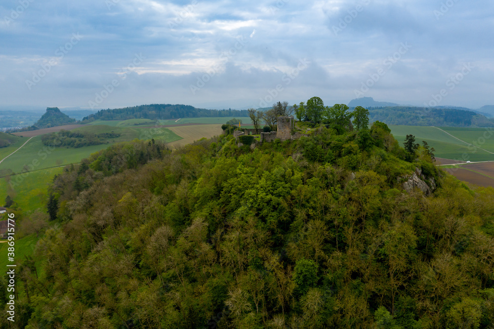 Aerial view of a forested hill with a castle ruin on top of it