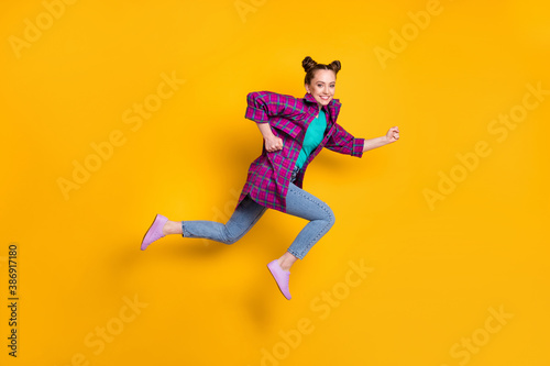 Full length profile photo of pretty teen lady jump high up run race marathon excited winner competition leader wear casual plaid shirt sneakers jeans isolated yellow vivid color background